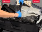 Funkcjonariusz otwiera walizkę, widoczne pakiety suszu w przezroczystej folii